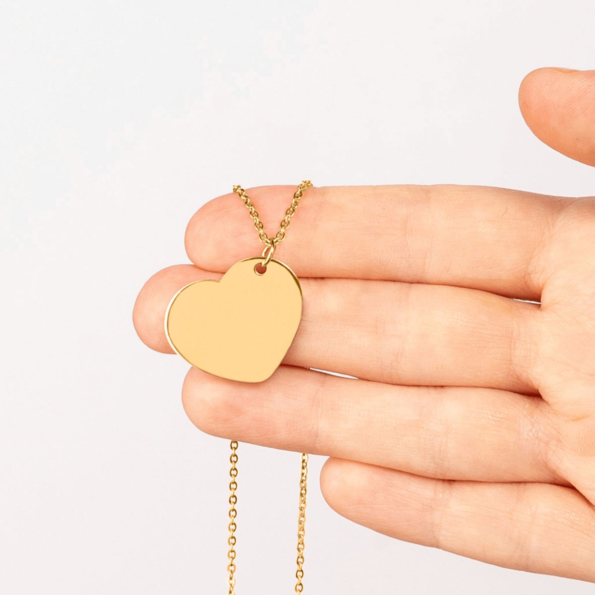 Pendentif cœur gravé tenu dans la main – Éclat Gravé